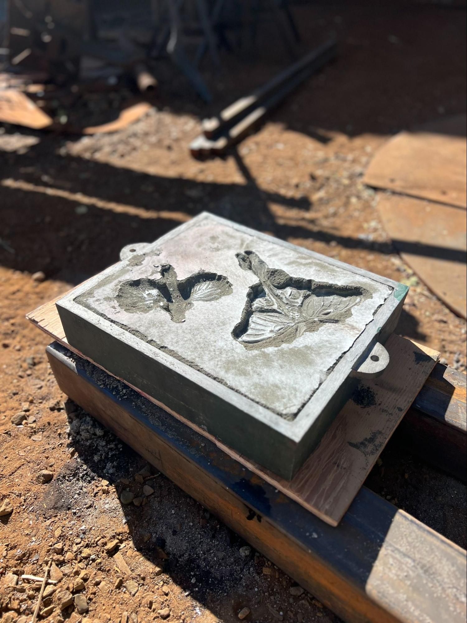 Concrete mold with raised letter design on a workbench outdoors