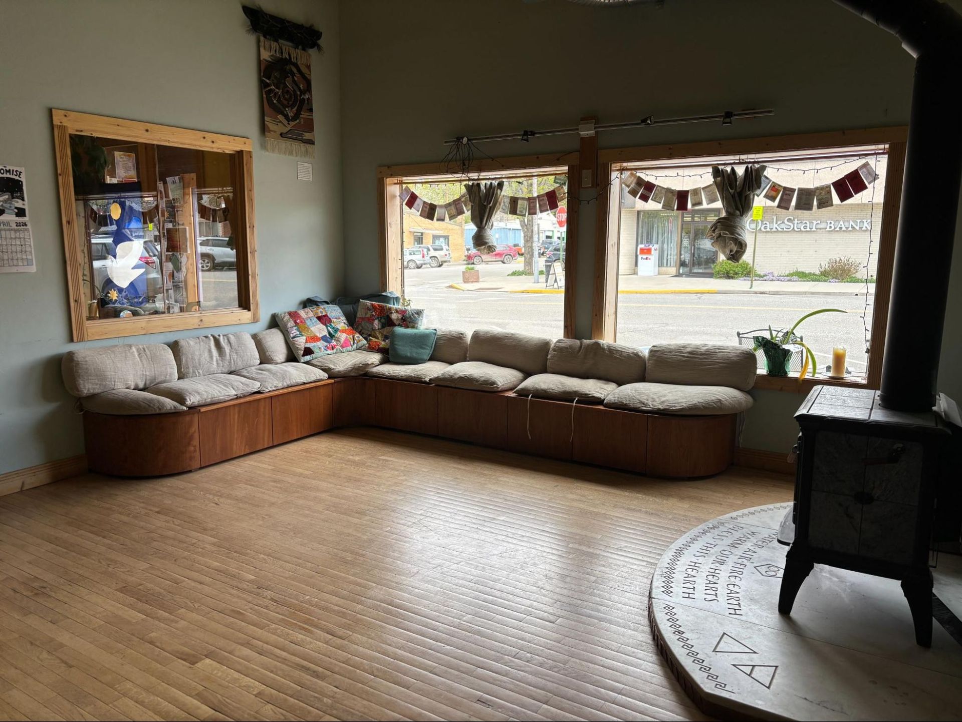 Empty cozy living room with tan sectional by large windows and a black stove on a round rug