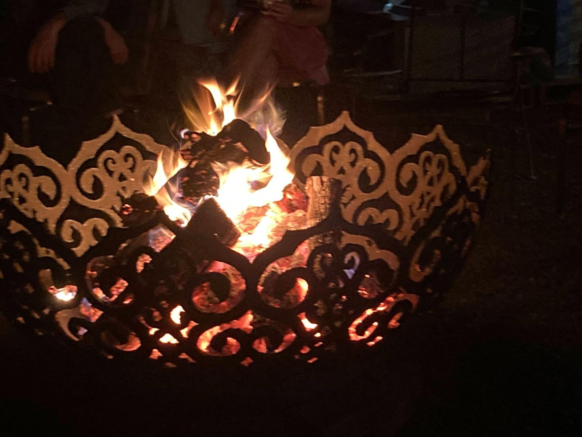 Decorative metal fire pit with a glowing campfire at night