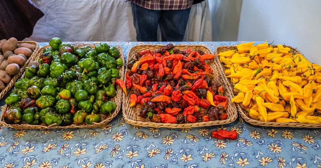 Three trays of colorful fried vegetables on a patterned cloth at a market stall