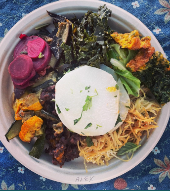 Colorful bowl of assorted vegetables and greens with a white rice dome on a patterned blue tablecloth