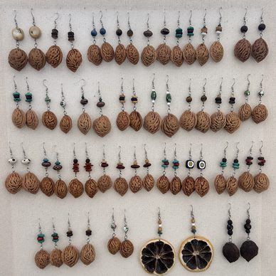 Rows of handmade brown beaded earrings hanging on display, with a few black flower-shaped pairs at the bottom.