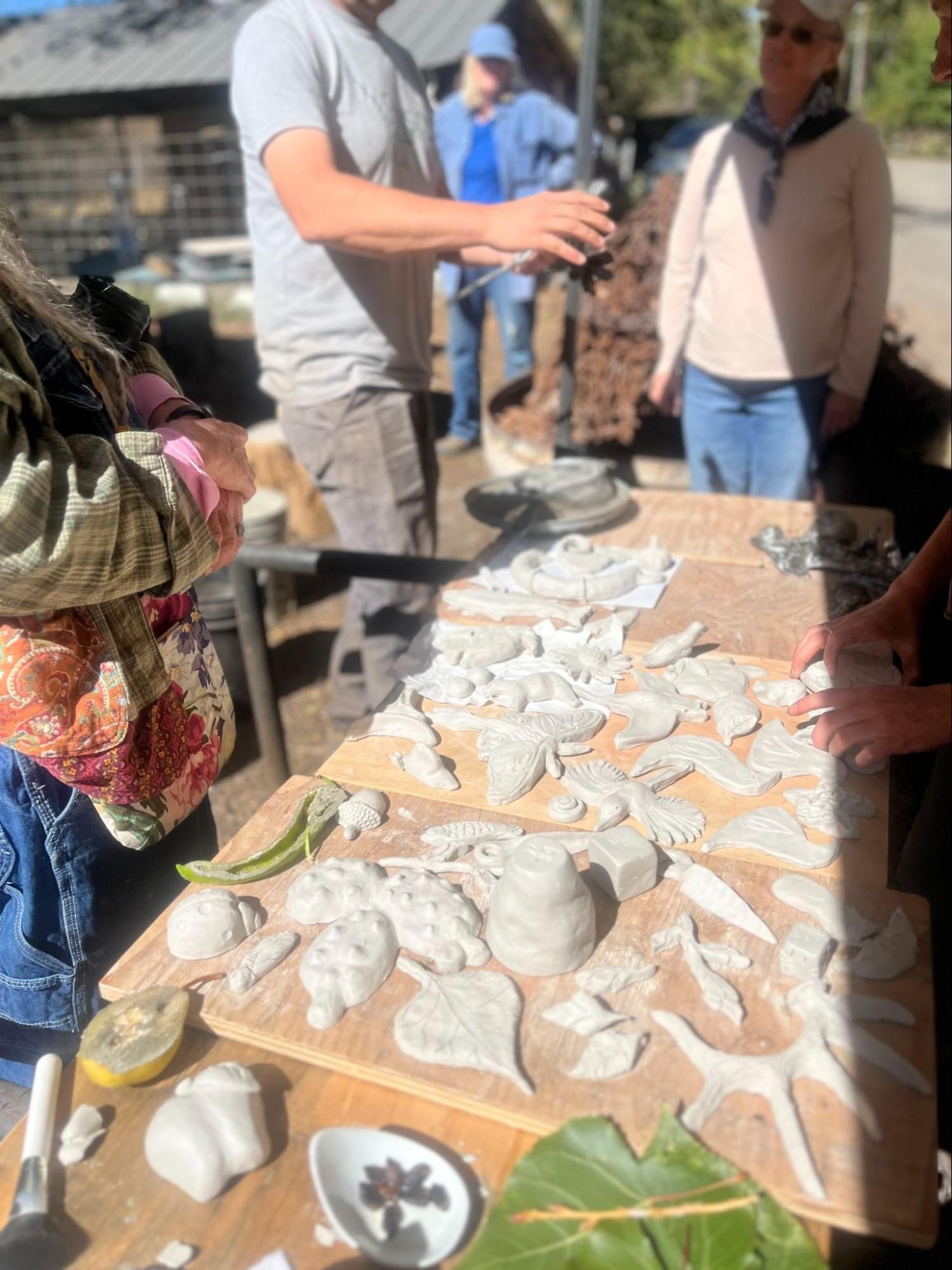 People sorting white shells on a wooden table outdoors in bright sunlight