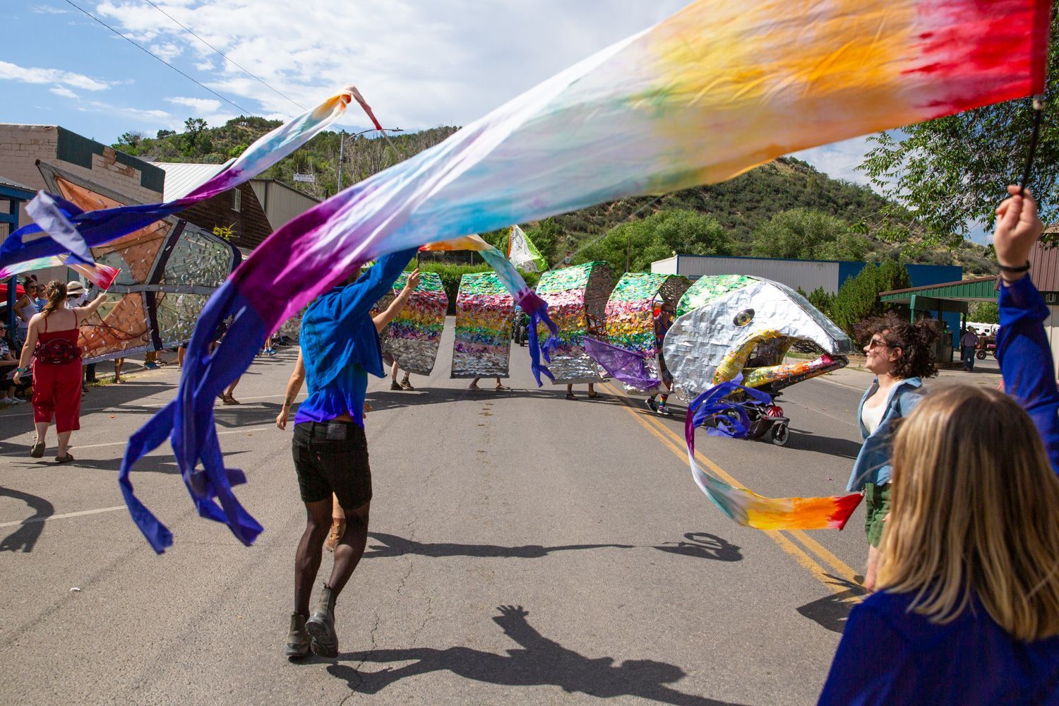 People waving rainbow flags in a street parade on a sunny day