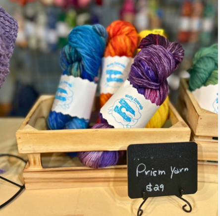 Colorful skeins of Prism Yarn in a wooden crate with a $29 price sign.