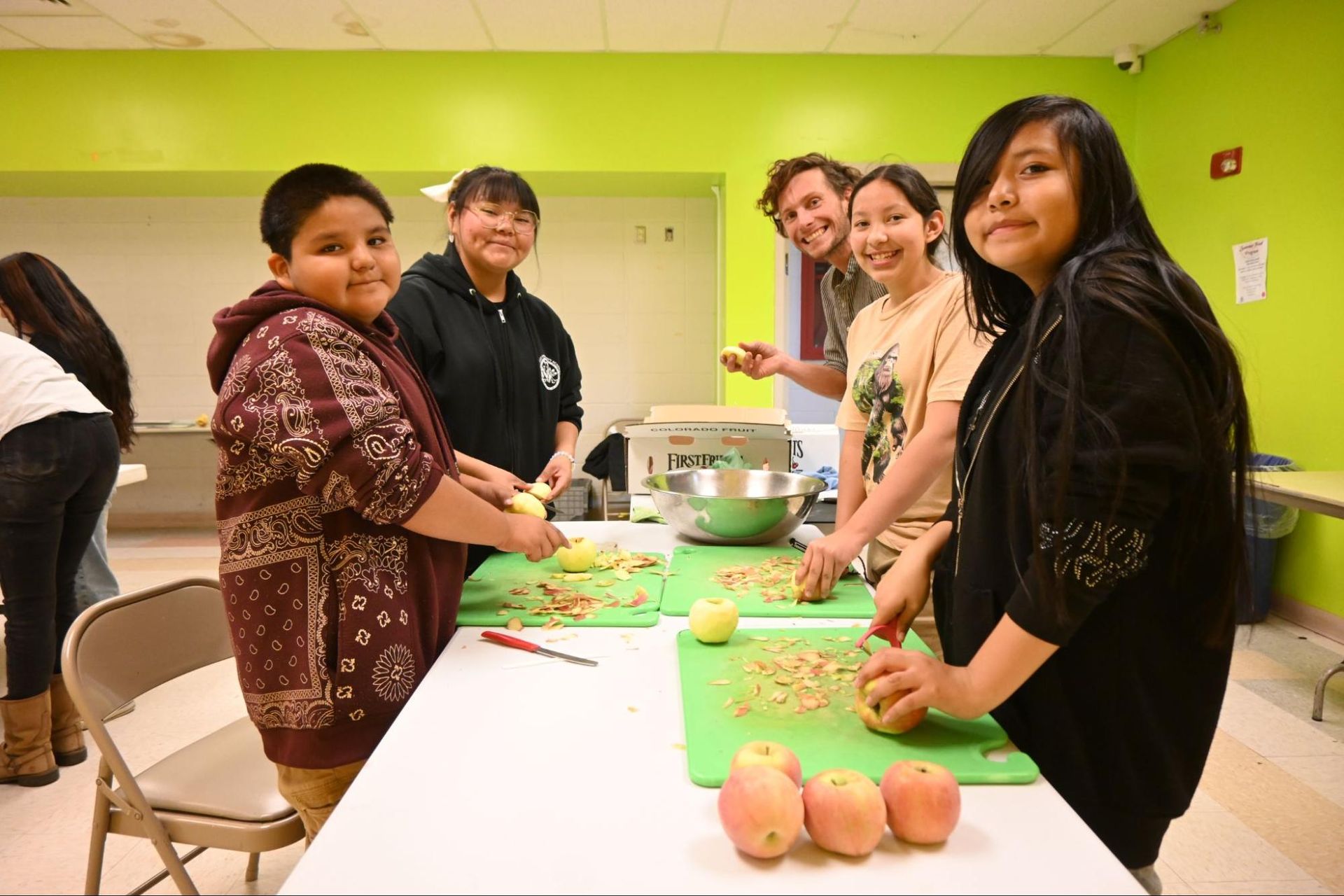 People gathered around a table preparing food in a bright green room