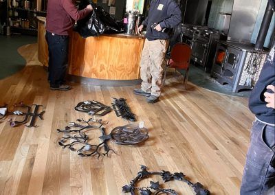 Scattered spider-like props on a wooden floor beside a bar counter, with two people standing nearby
