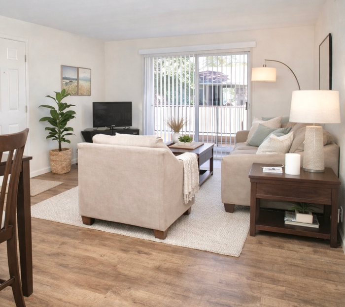 Pensacola apartment living room with natural light coming from balcony, decorated with natural colors and wood floors