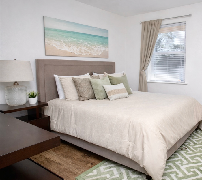 apartment bedroom decorated with a bed, side table and TV stand 