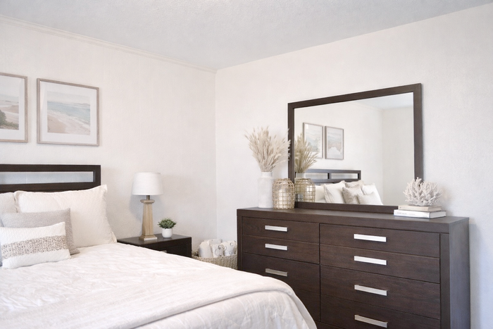 apartment bedroom decorated with a bed, side table and dresser