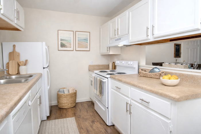 pensacola apartment kitchen with white appliances, white cabinets, and wood flooring