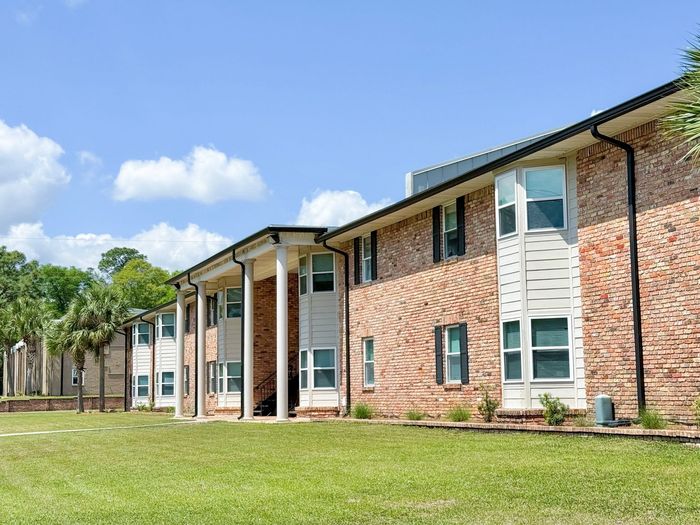 pensacola apartment complex with large pillars and two palm trees at the corner