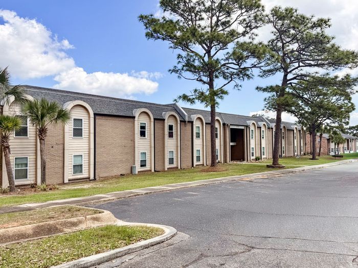 pensacola apartment complex with large pine trees in courtyard