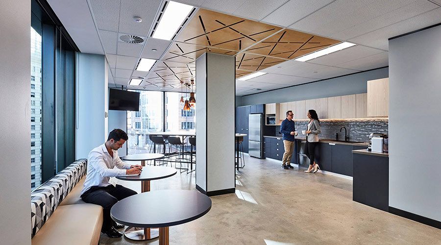 A man is sitting at a table in a kitchen in an office building.