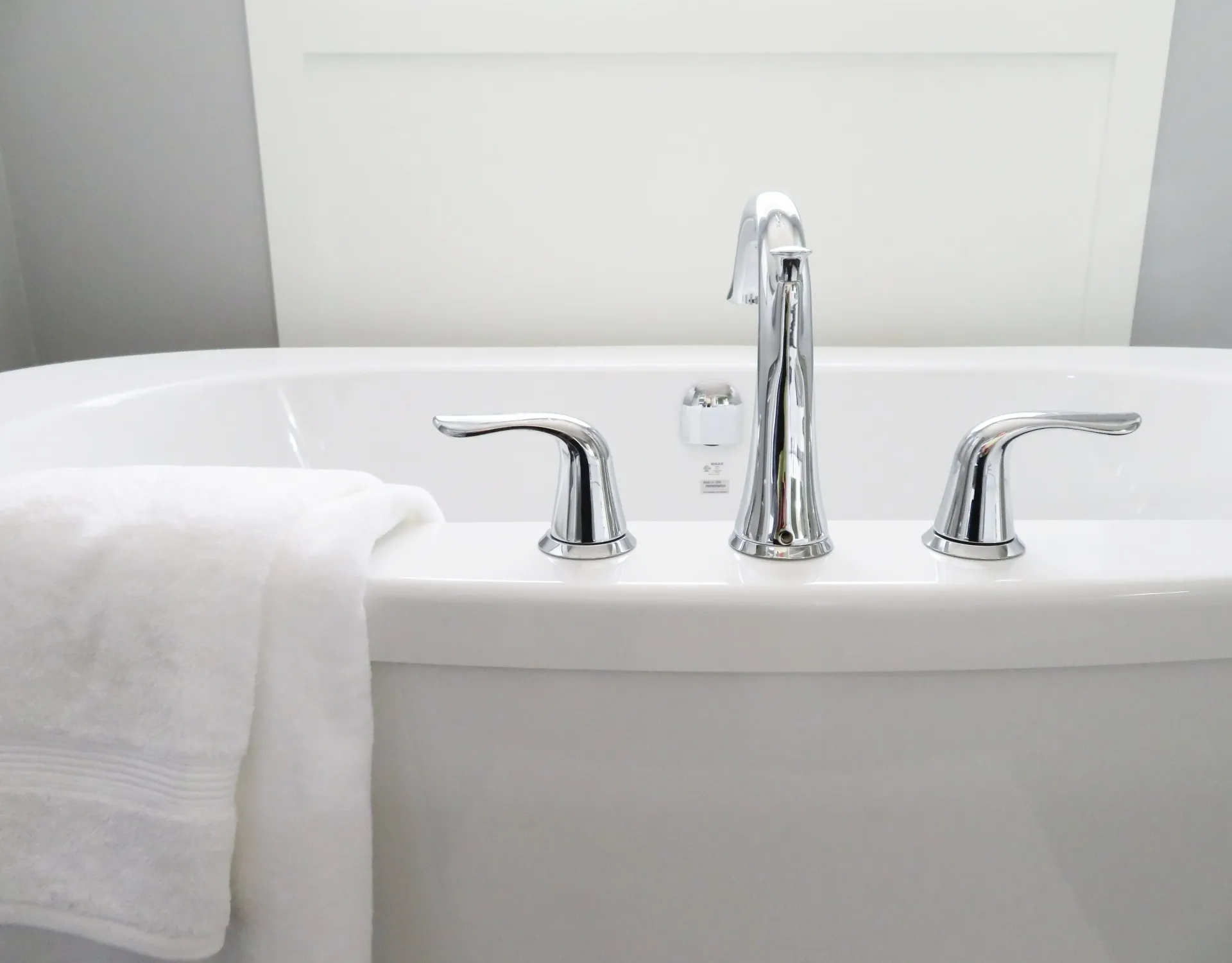 A white bathtub with chrome faucets and a white towel on the side.