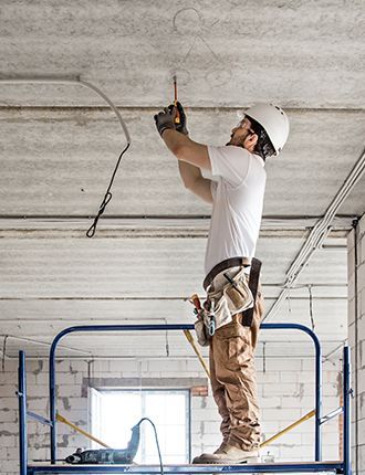 A man is standing on a scaffolding working on a ceiling.