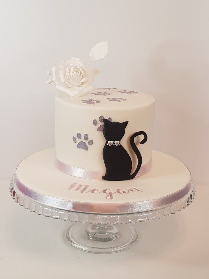 A white cake with a black cat on top of it