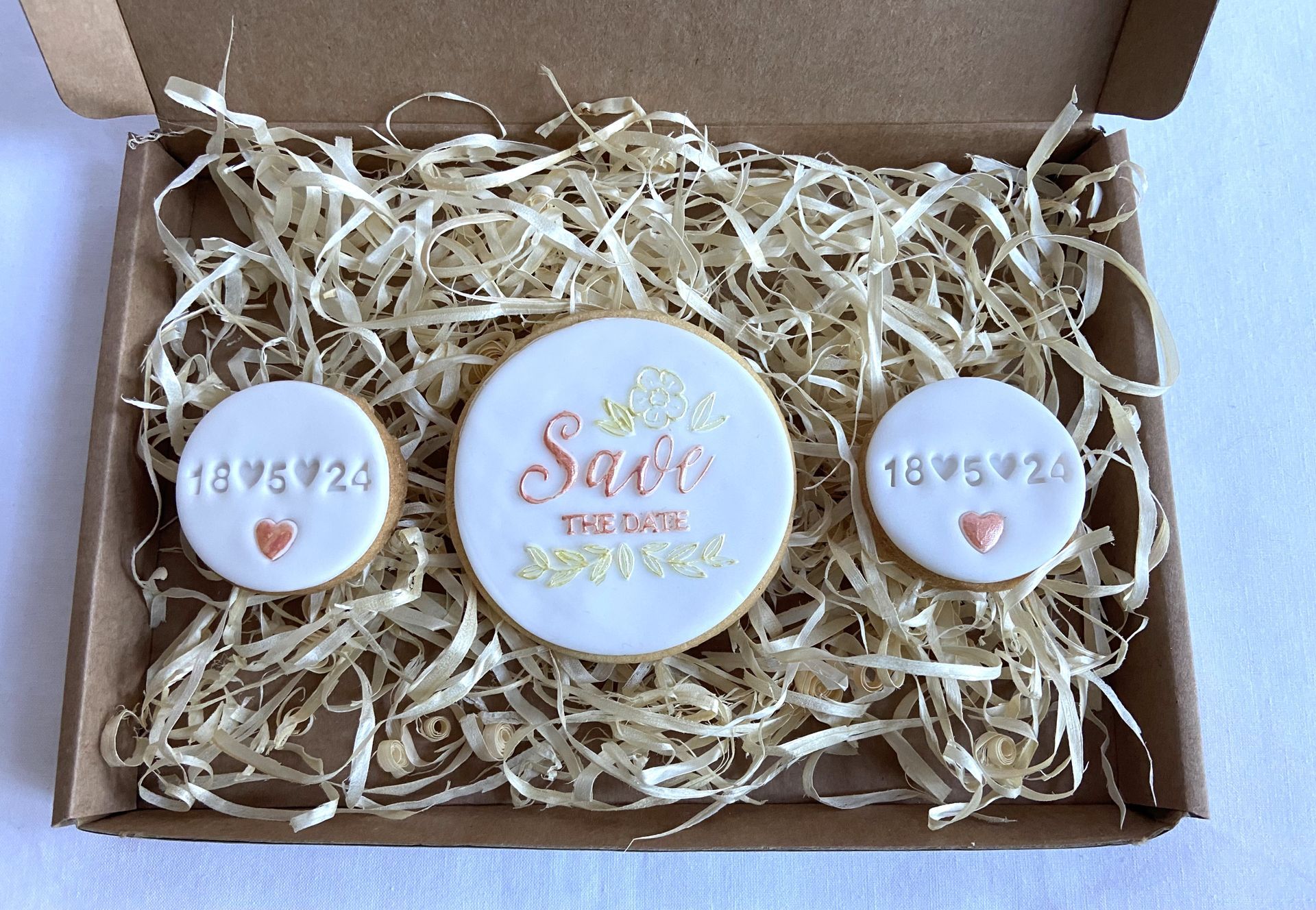 A box filled with straw and cookies that say save the date