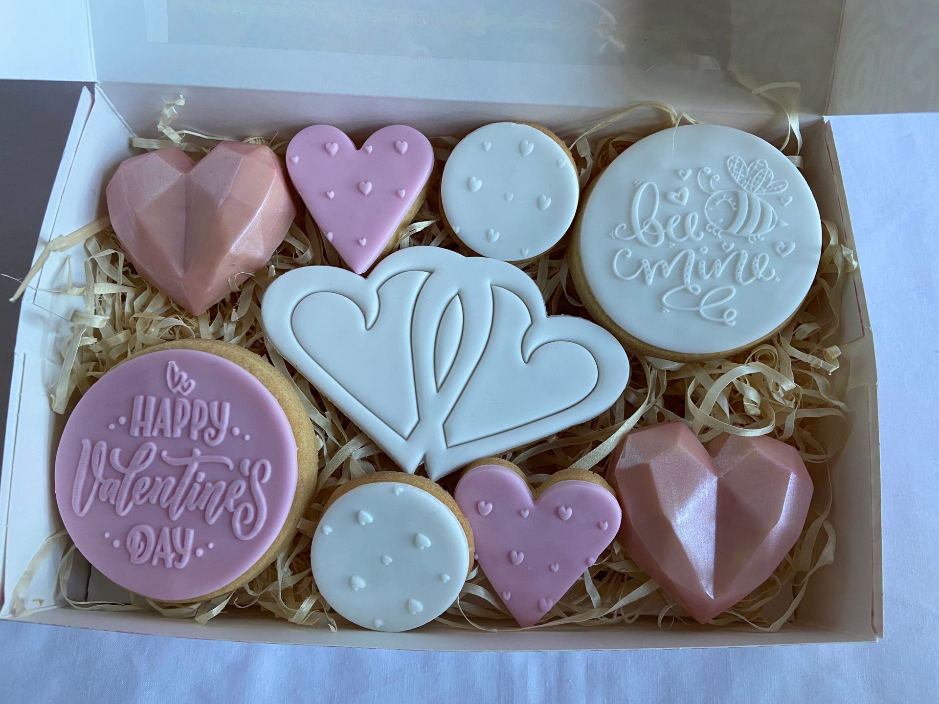 A box filled with valentine 's day cookies and chocolate hearts.