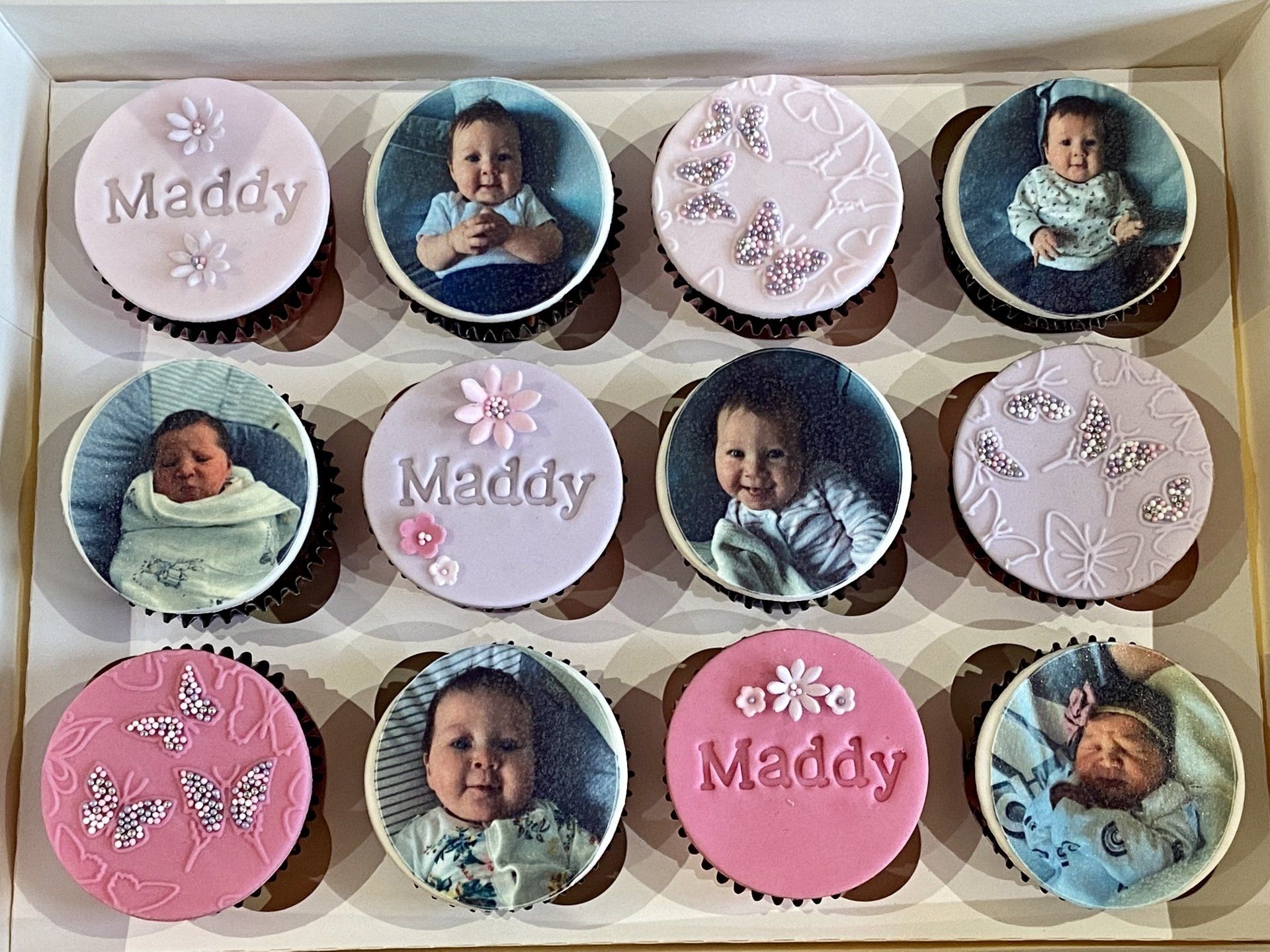 A box of cupcakes with pictures of a baby on them.