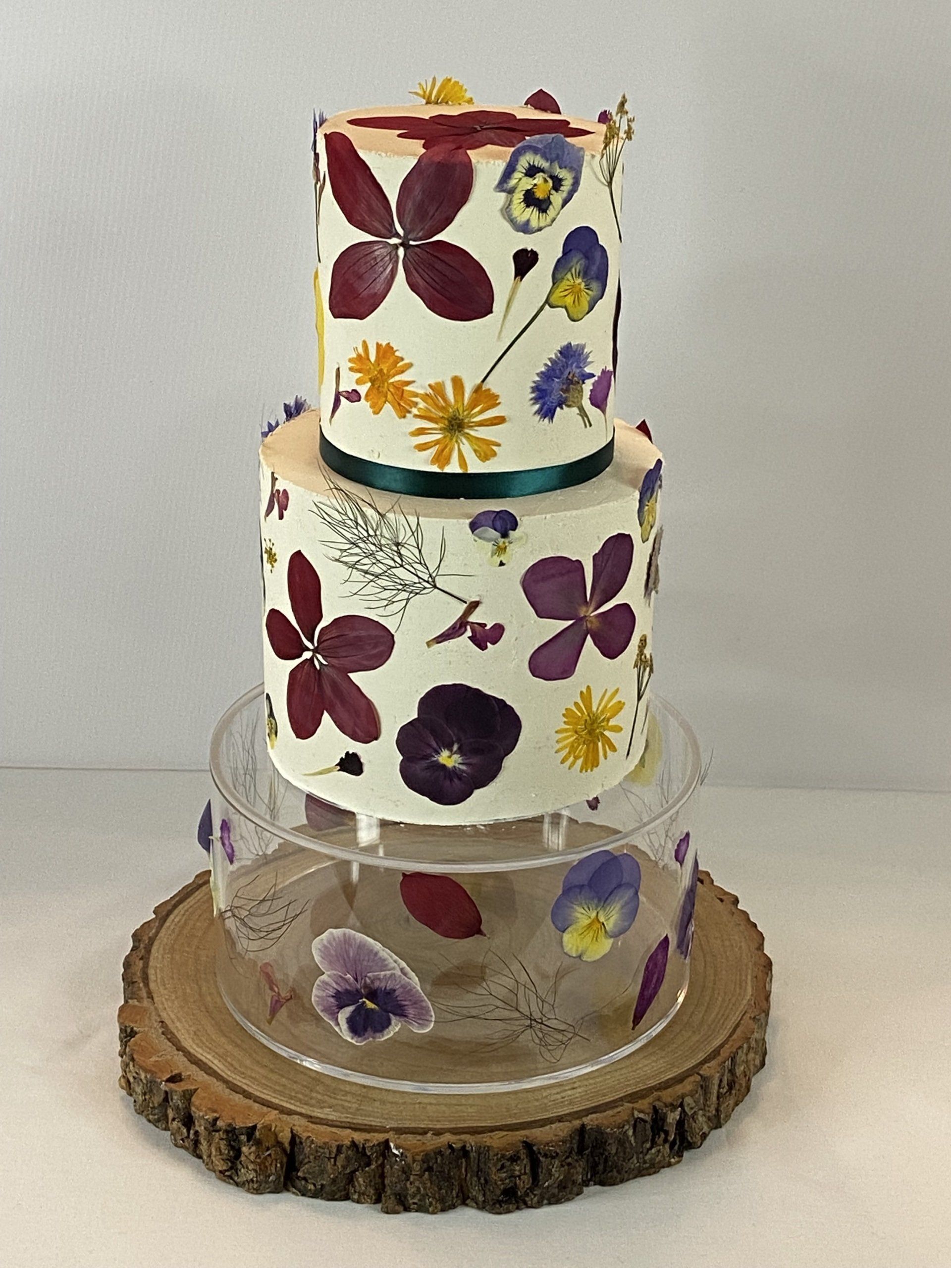 A three tiered cake with pressed flowers on it