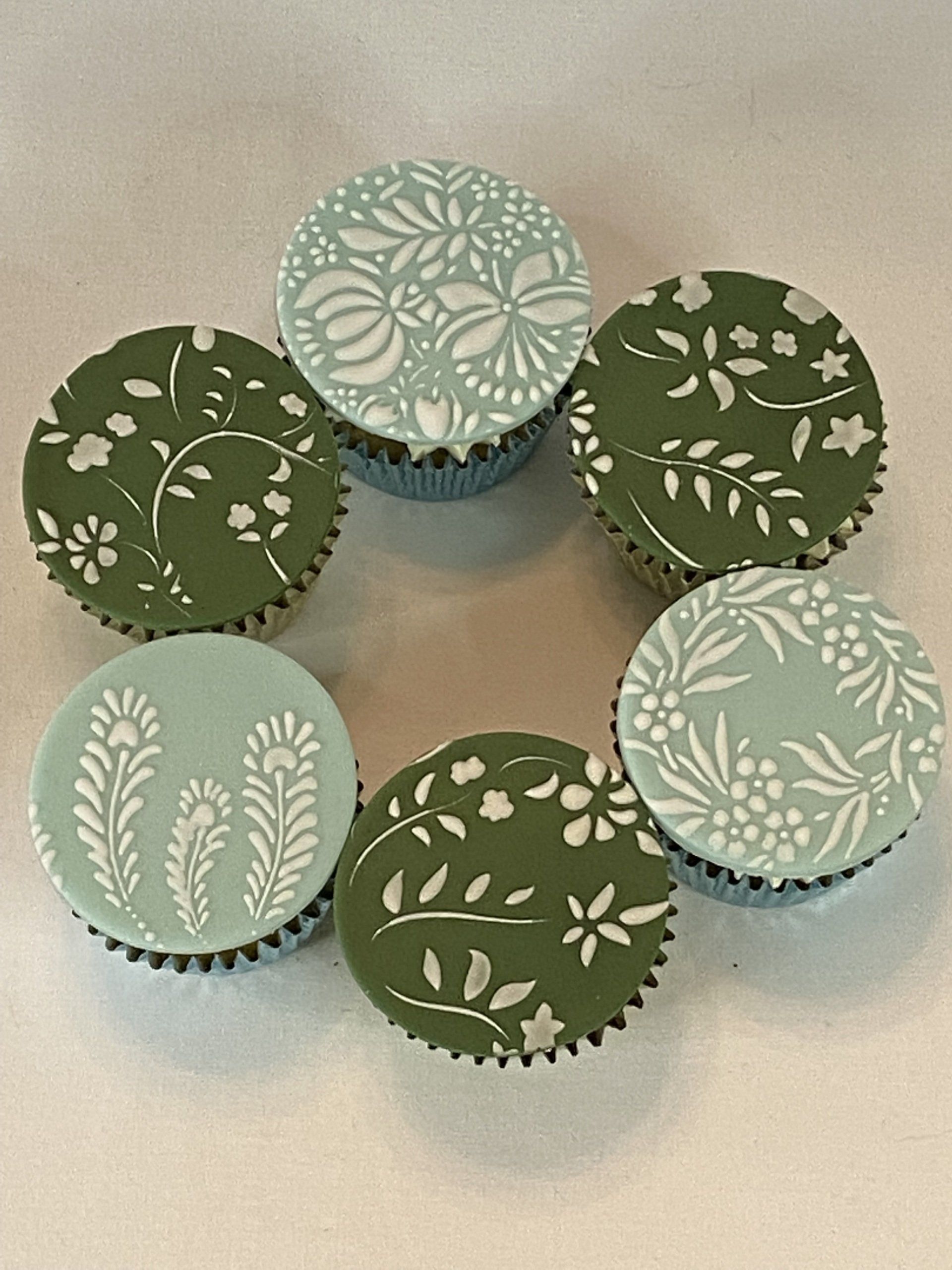 A group of green and white cupcakes with floral designs on them