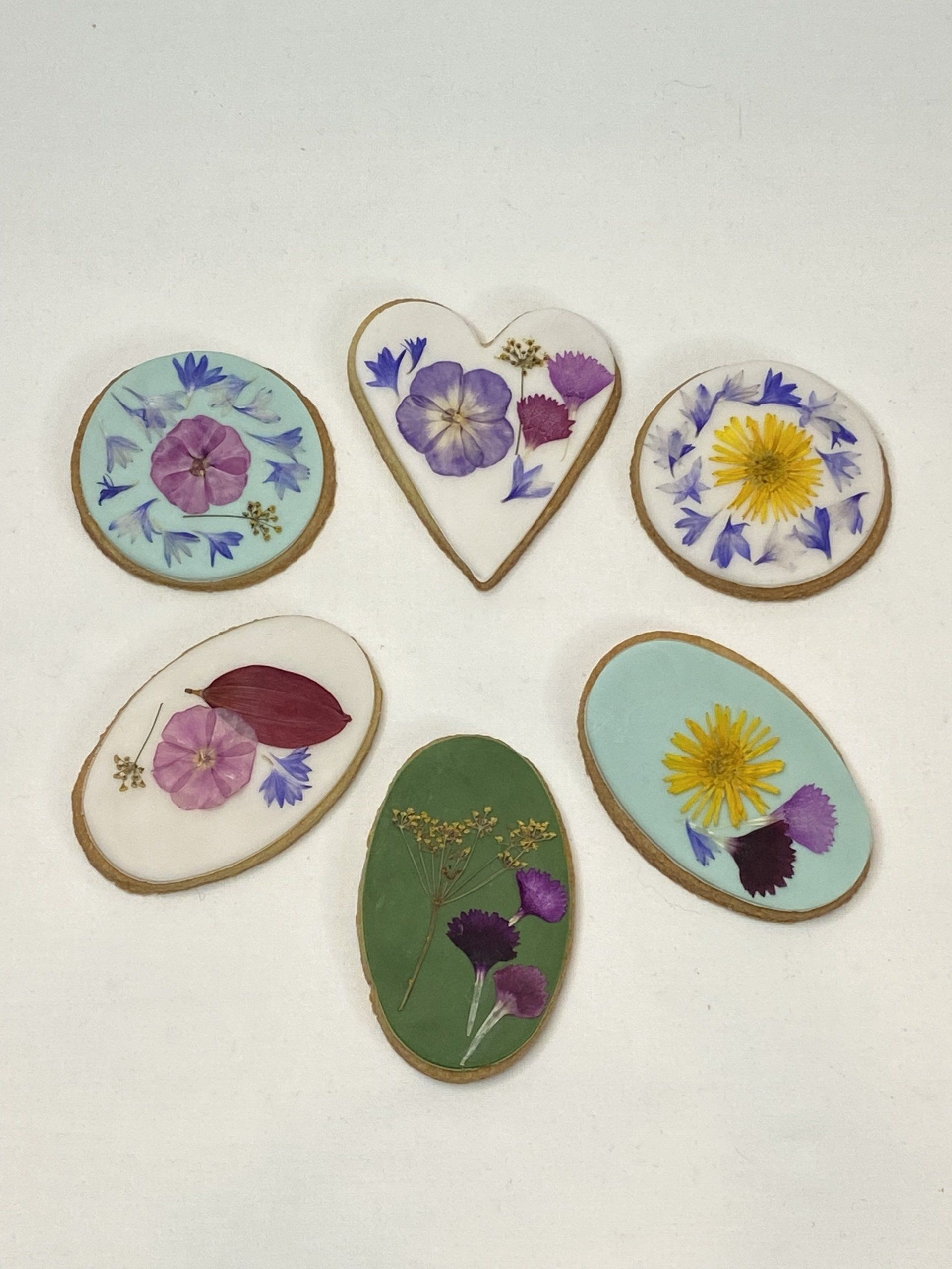 A heart shaped cookie is surrounded by other cookies with flowers on them