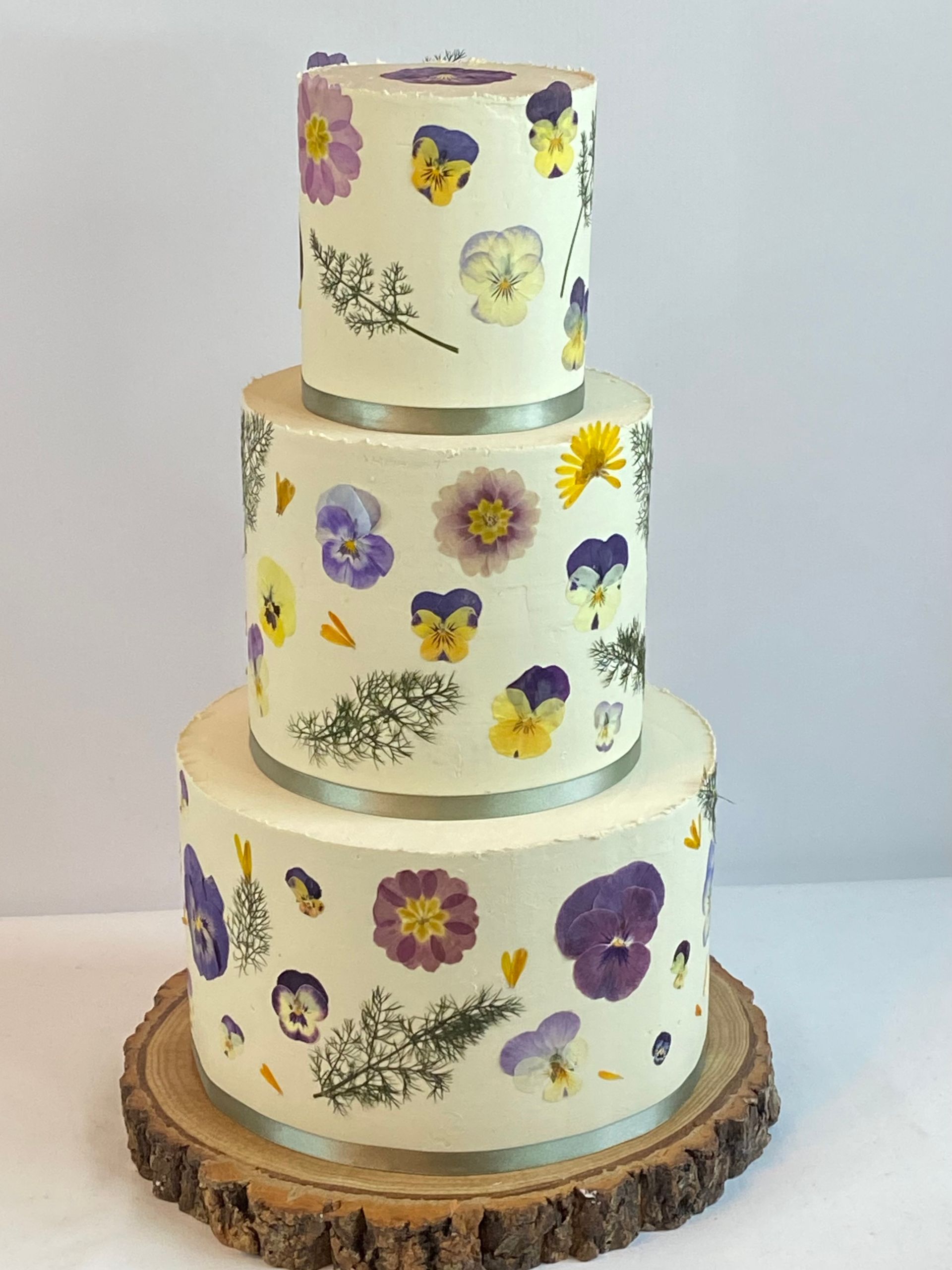 A white cake with purple and yellow flowers on it
