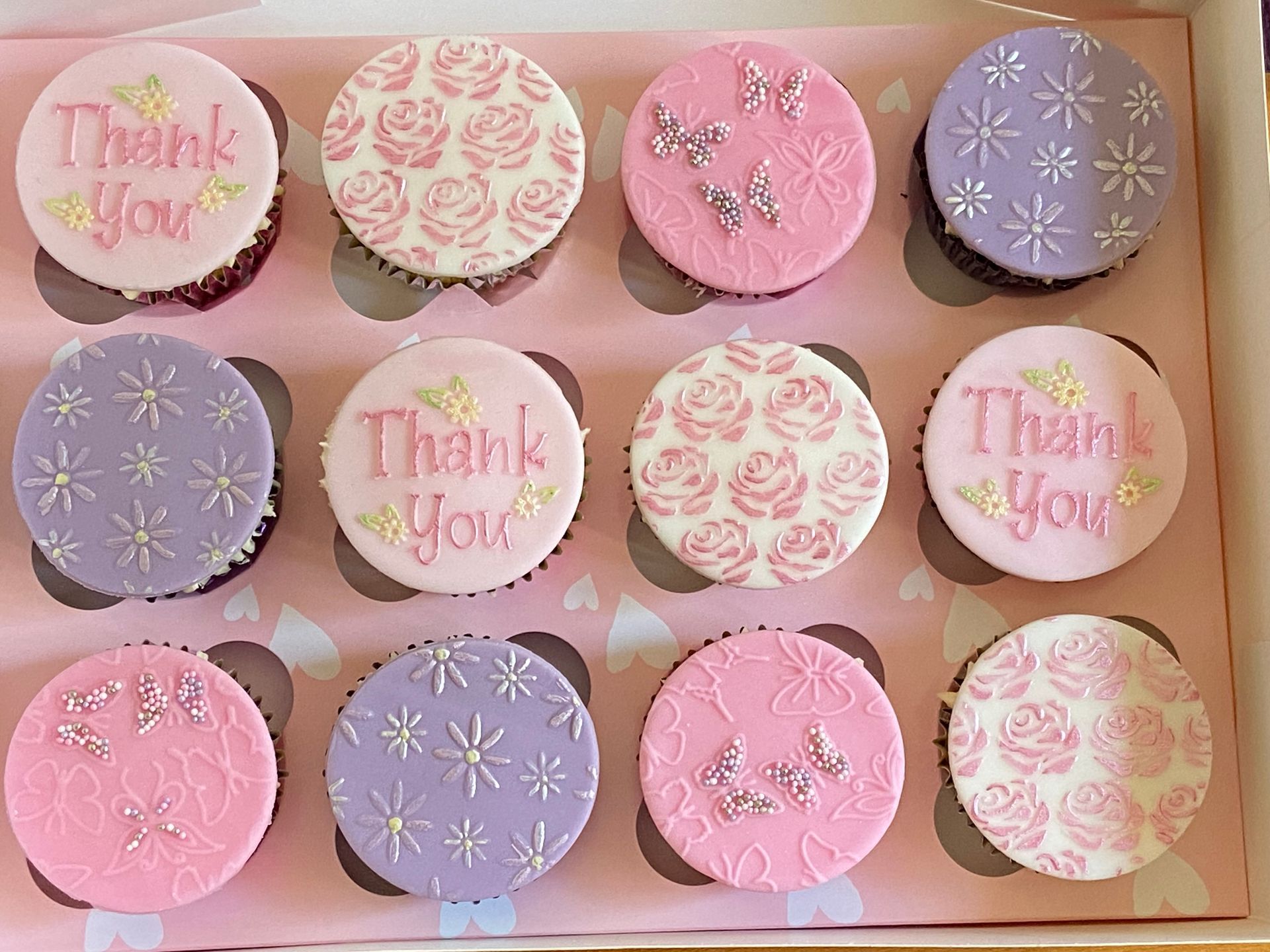 A box of pink and purple thank you cupcakes