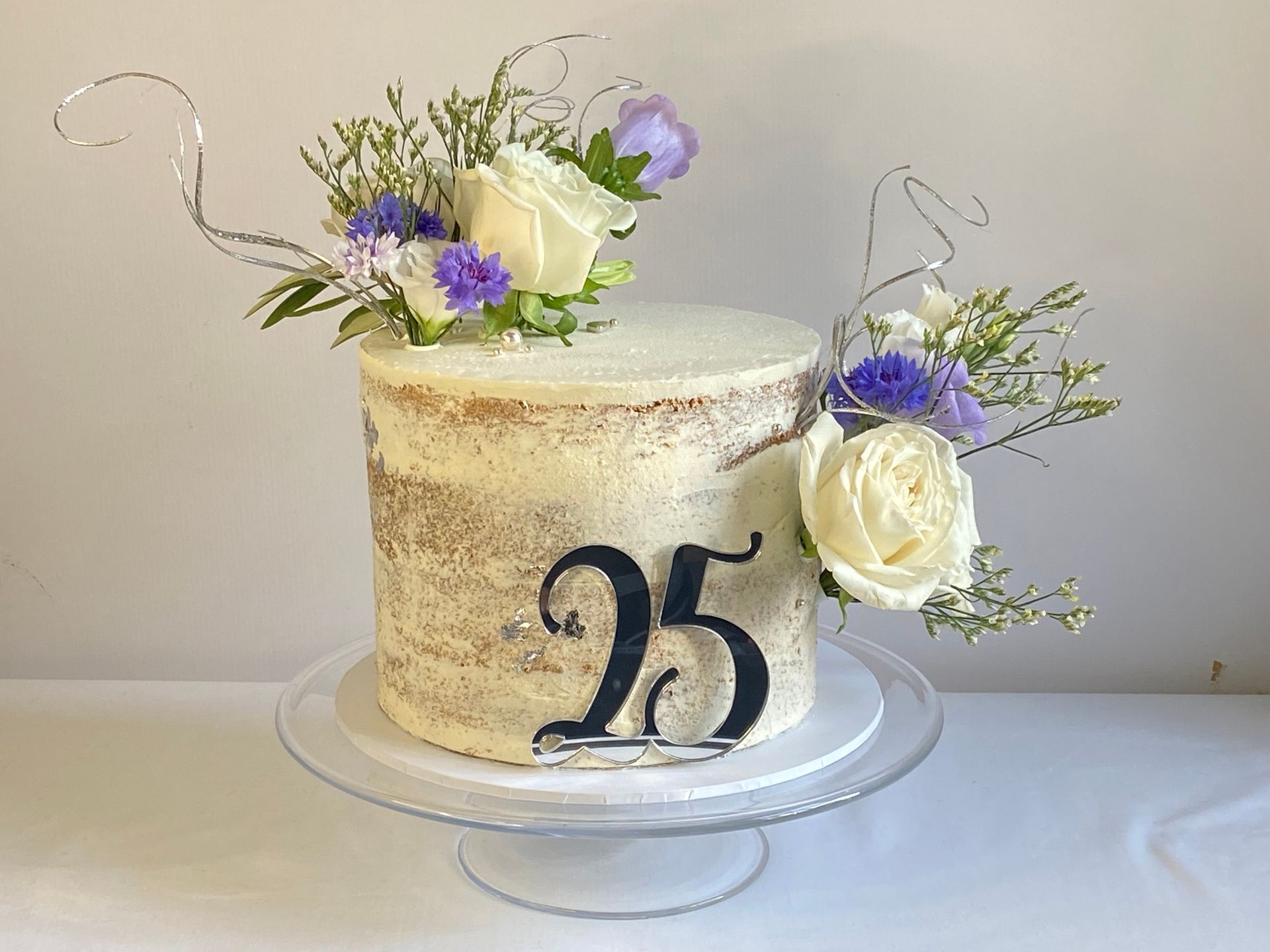 A cake with flowers on top of it and the number 25 on it.