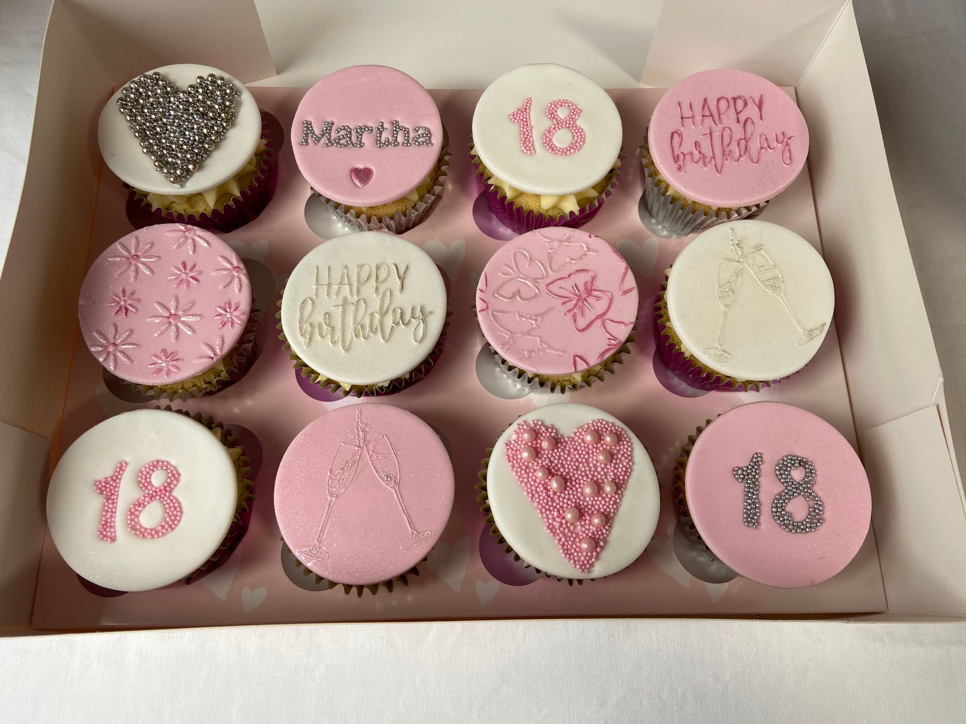 A box of pink and white cupcakes for a 18th birthday.