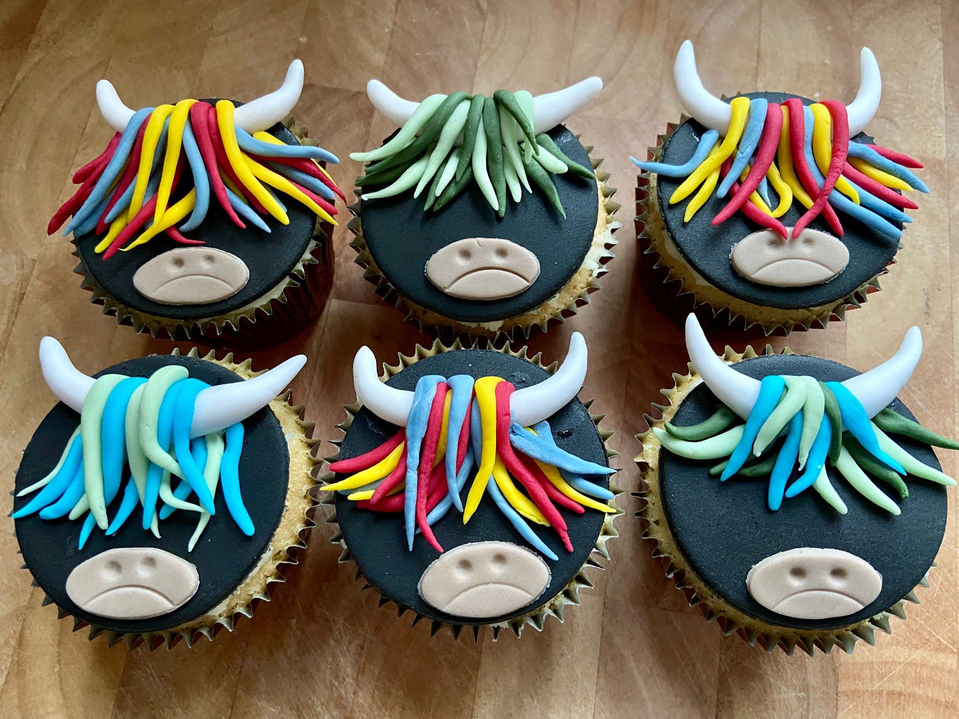 Six cupcakes decorated to look like cows with horns