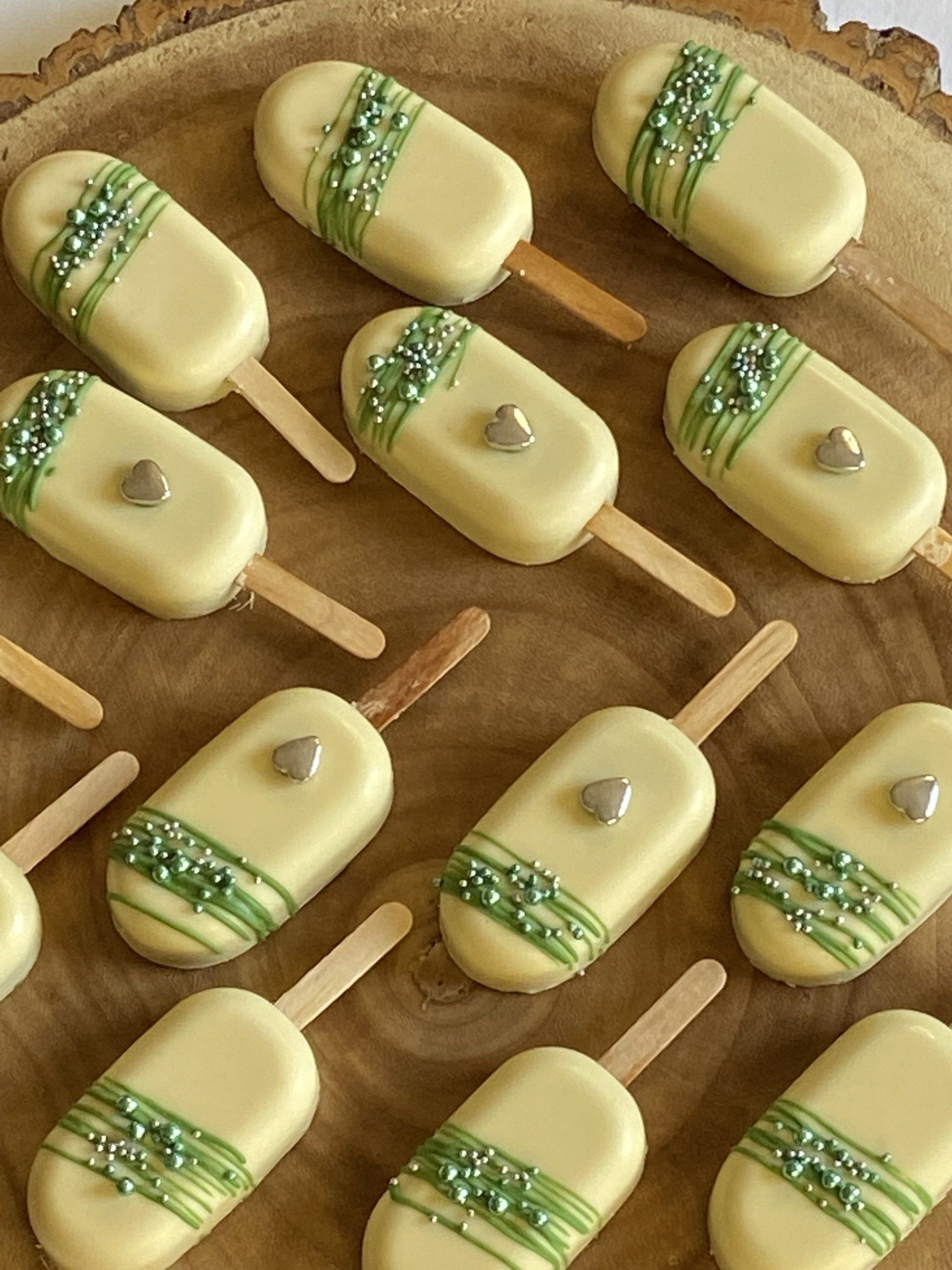 A bunch of white chocolate covered popsicles on a wooden table