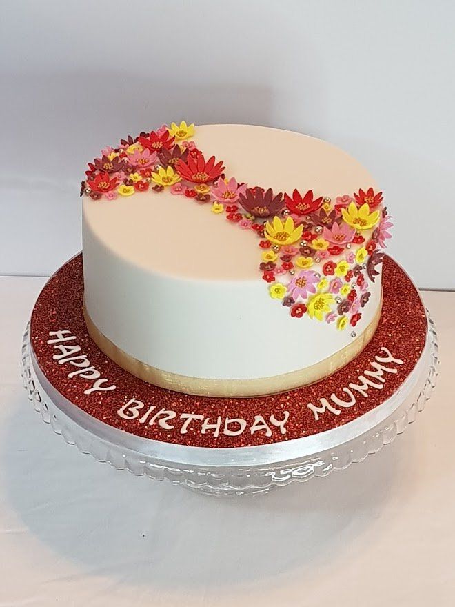 A birthday cake with flowers on it is on a glass plate.
