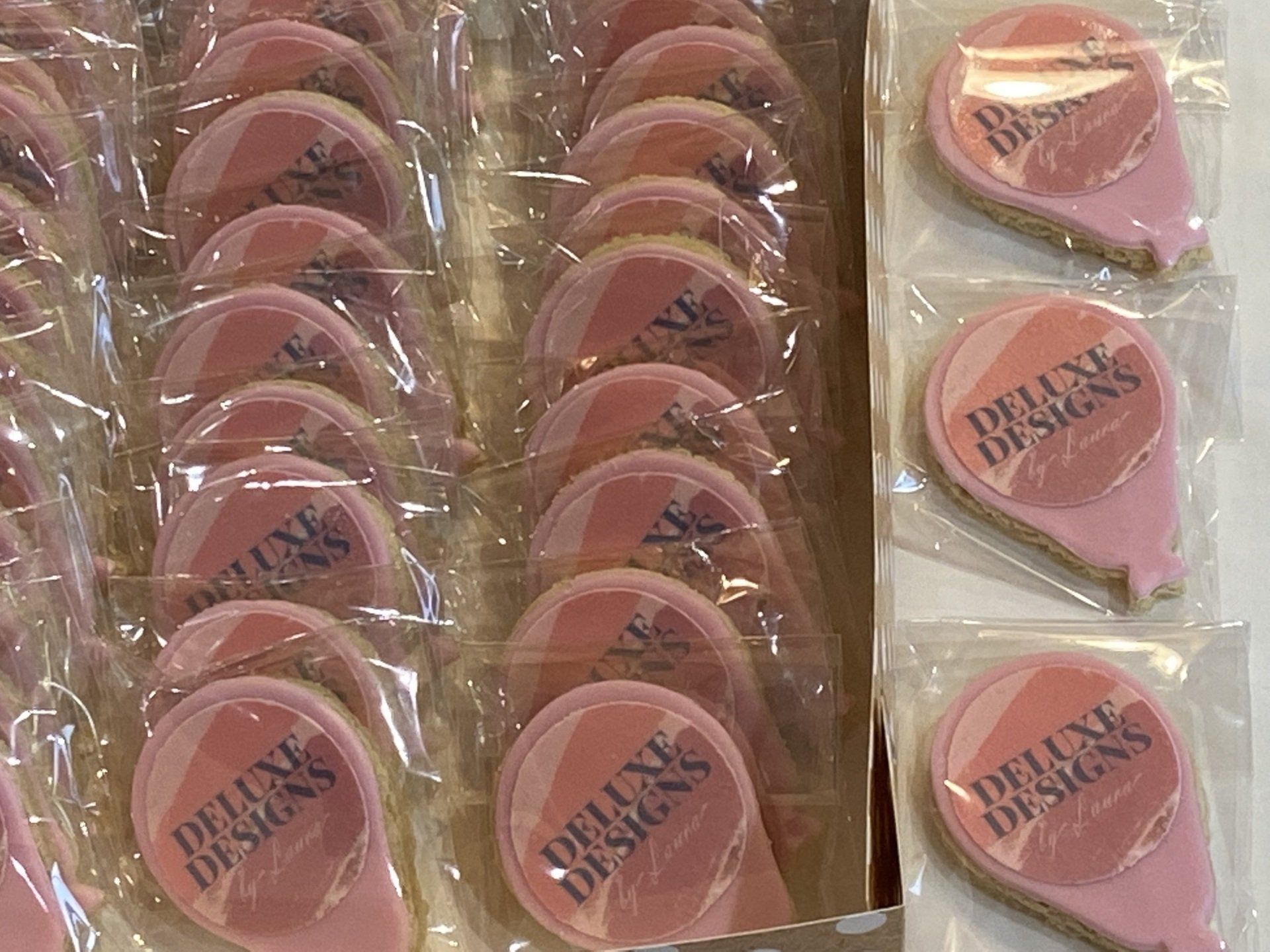 A box of pink deluxe designs cookies in plastic bags