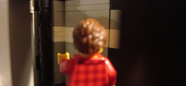 A lego figure is standing in a dark room