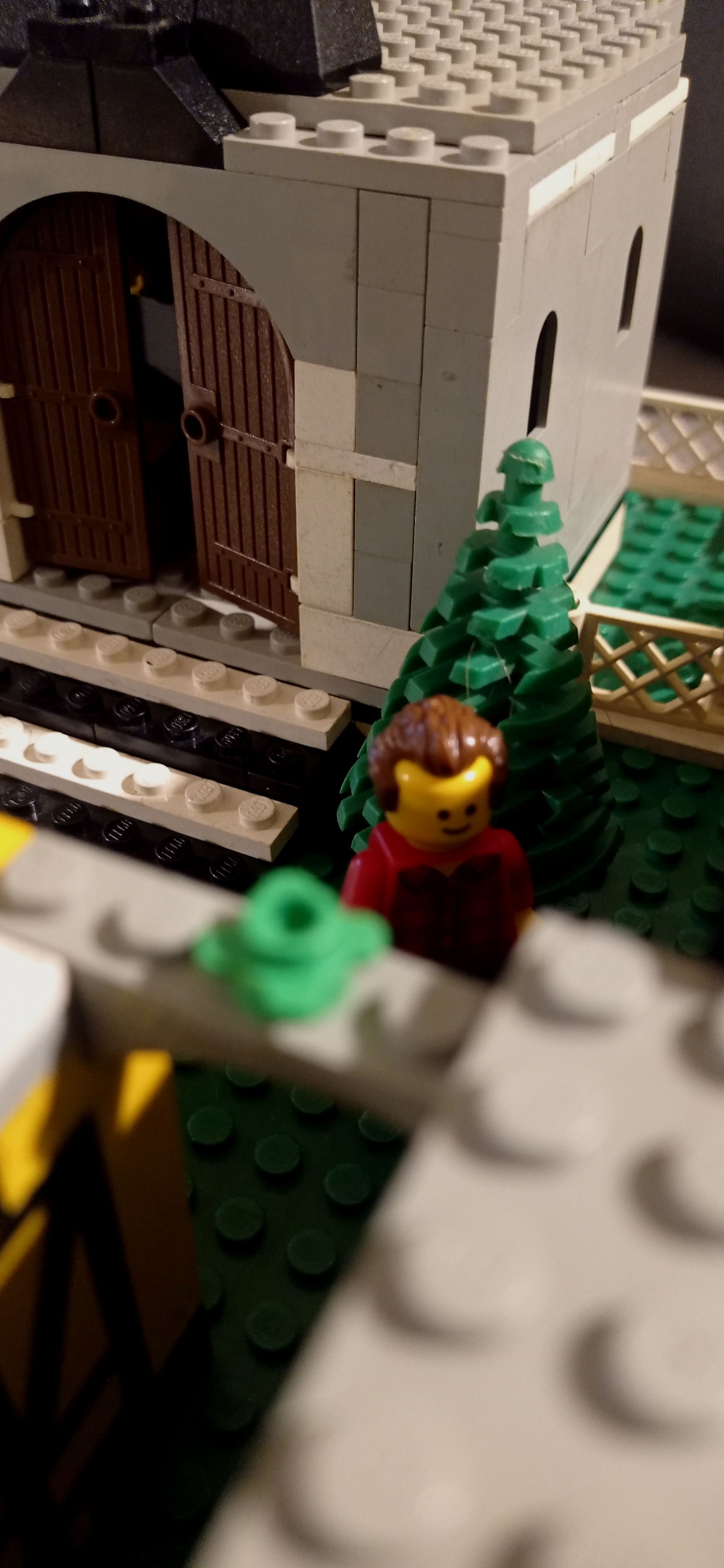 A lego man is standing in front of a building.