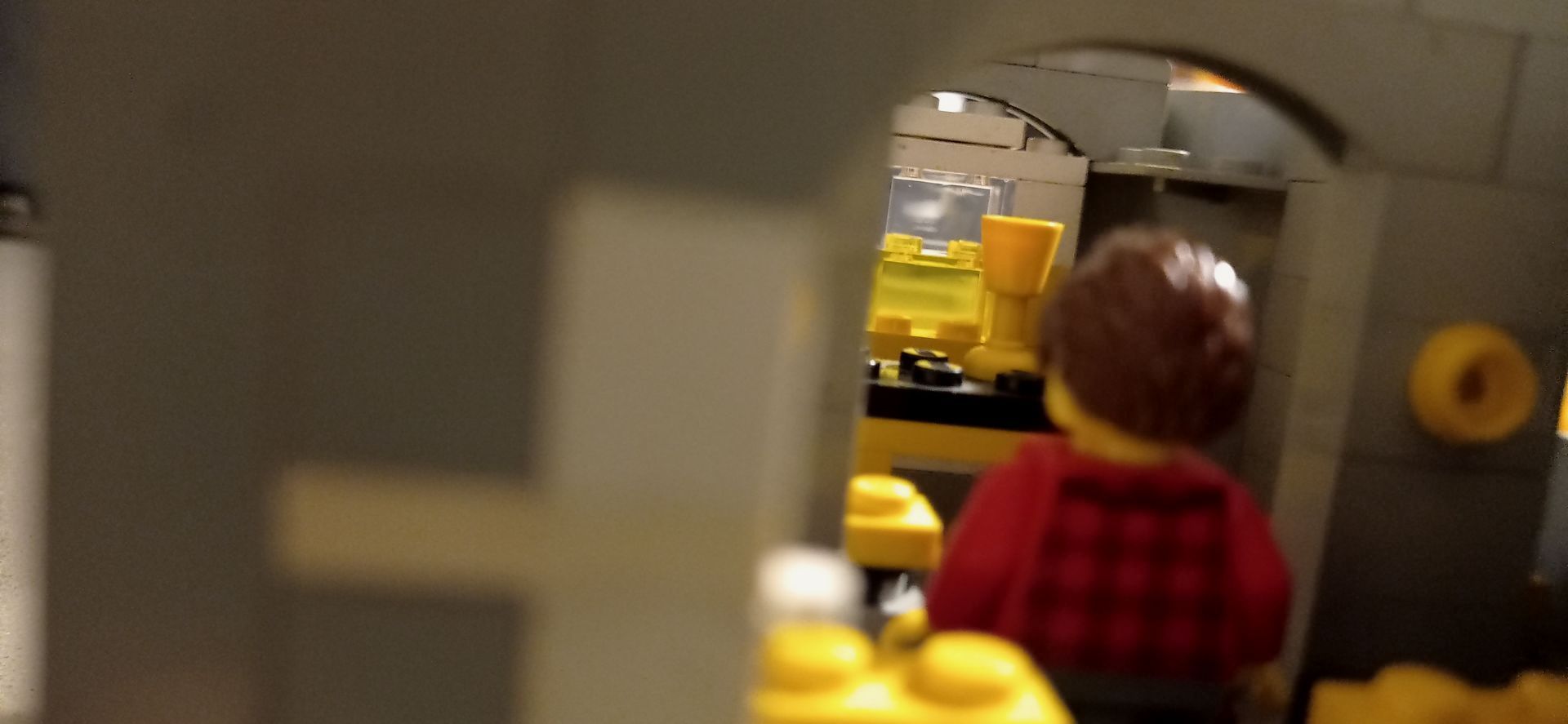 A lego man in a red shirt is standing in a room.