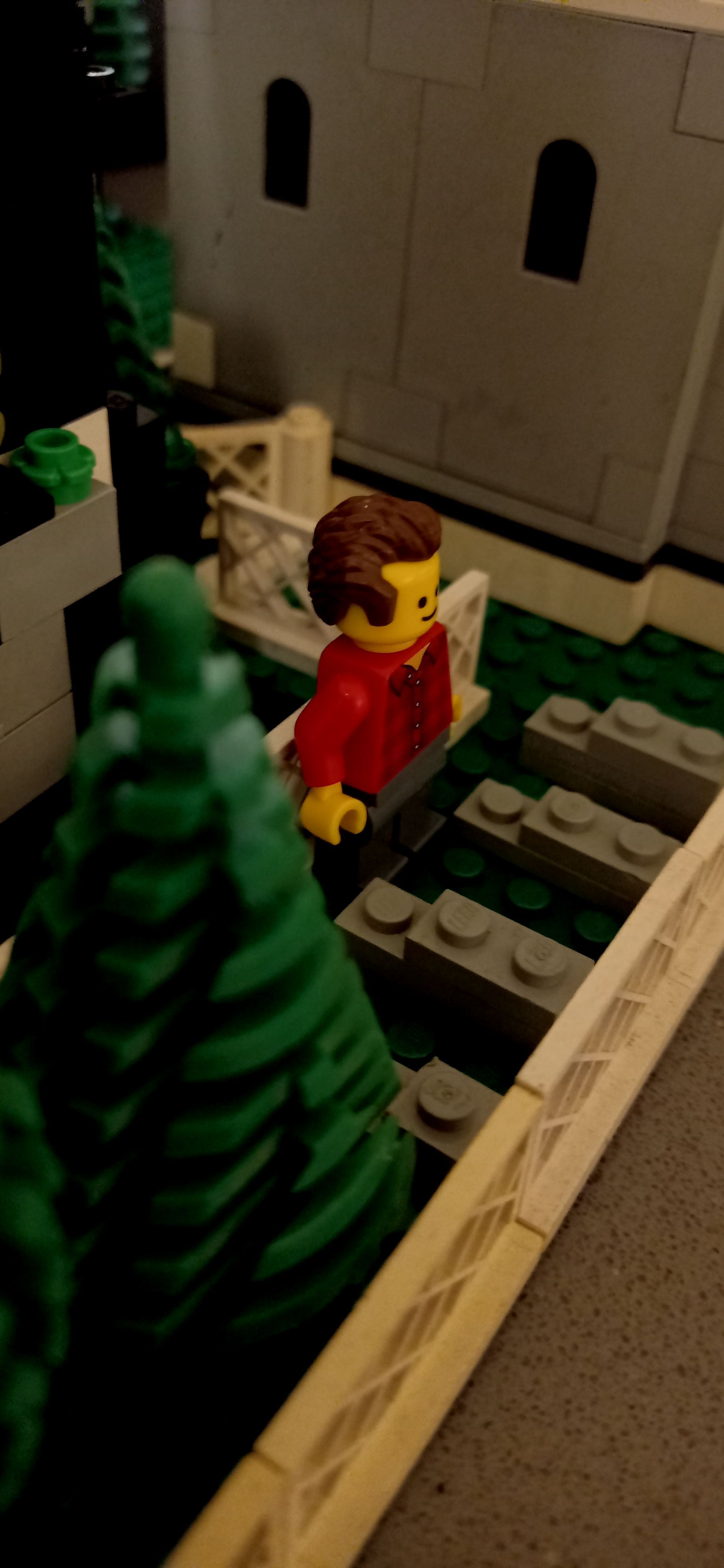 A lego man is standing on a set of train tracks.