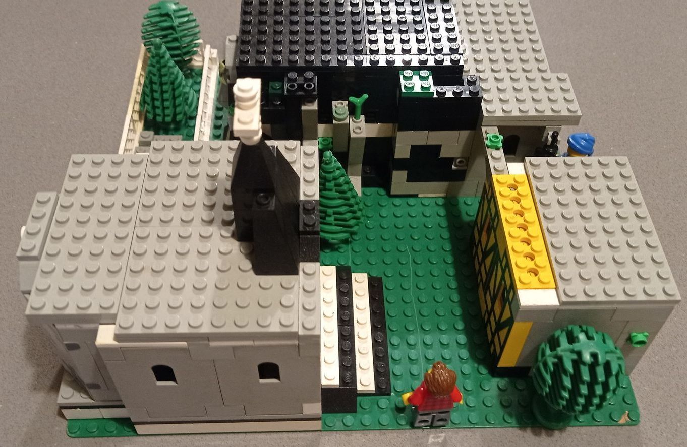 A lego model of a house with trees and a chimney