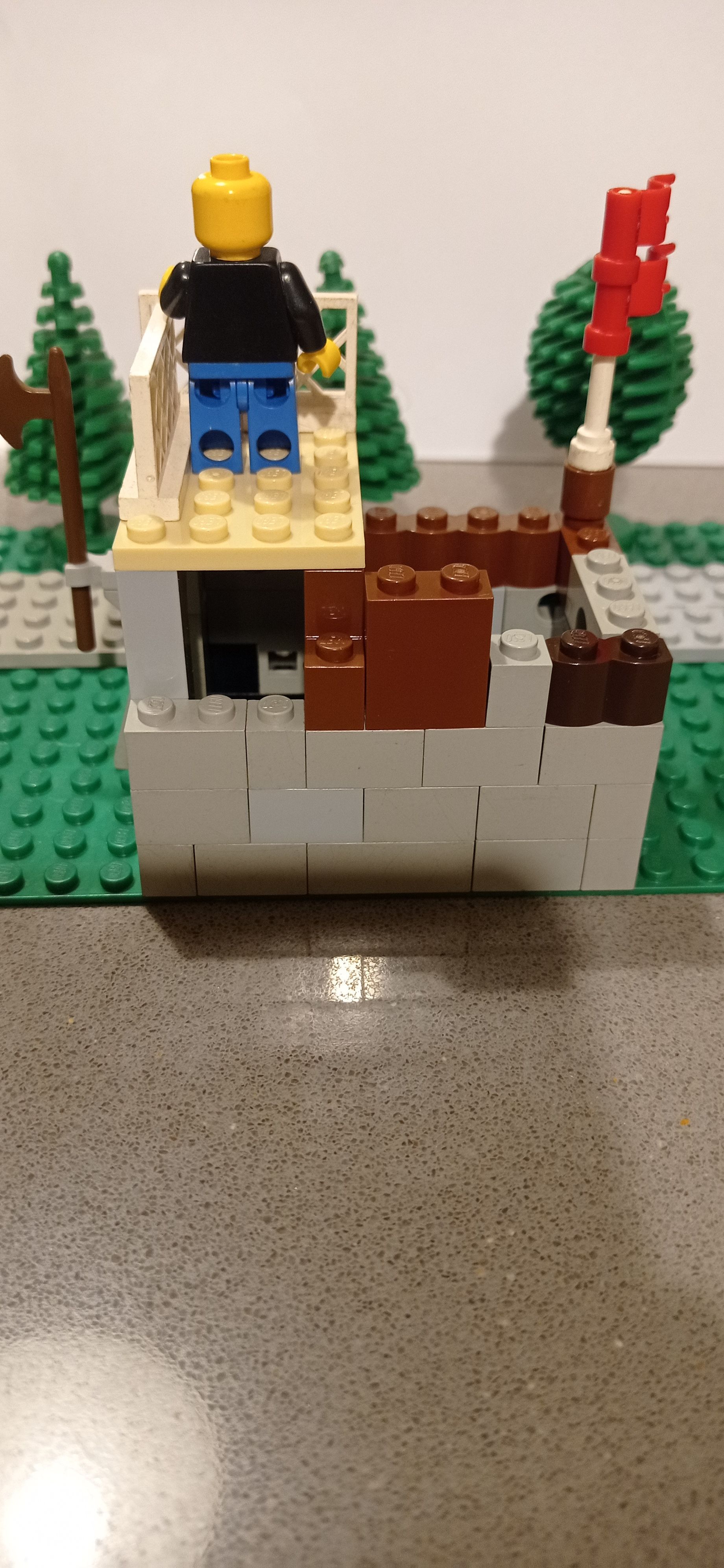 A lego man is sitting on top of a building.