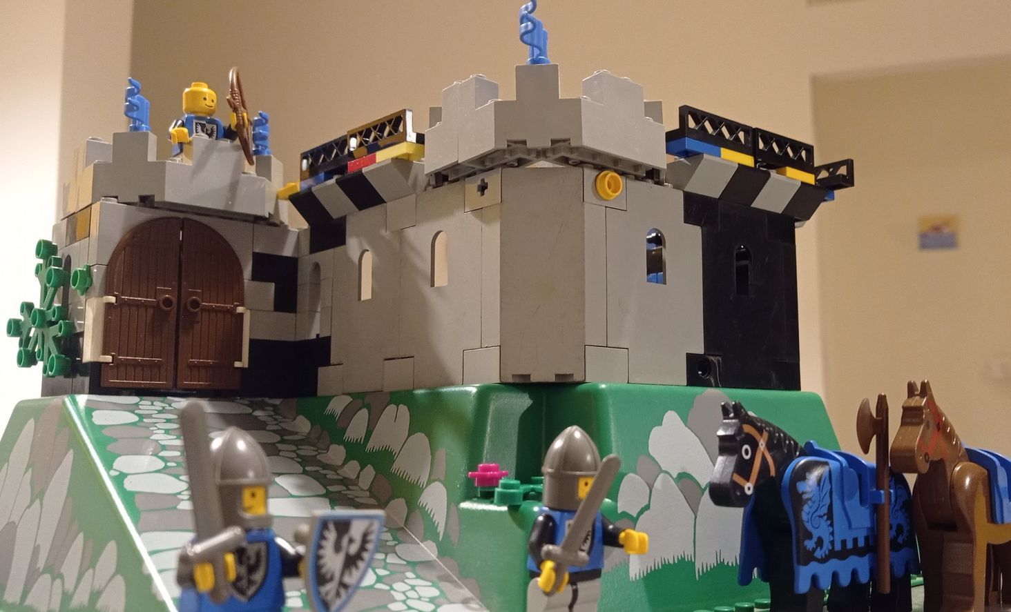 A lego castle with knights and horses in front of it