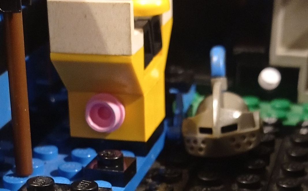 A close up of a lego train with a boat in the background