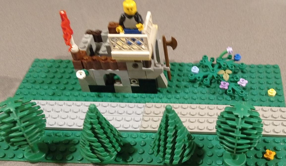 A lego model of a castle with trees and flowers