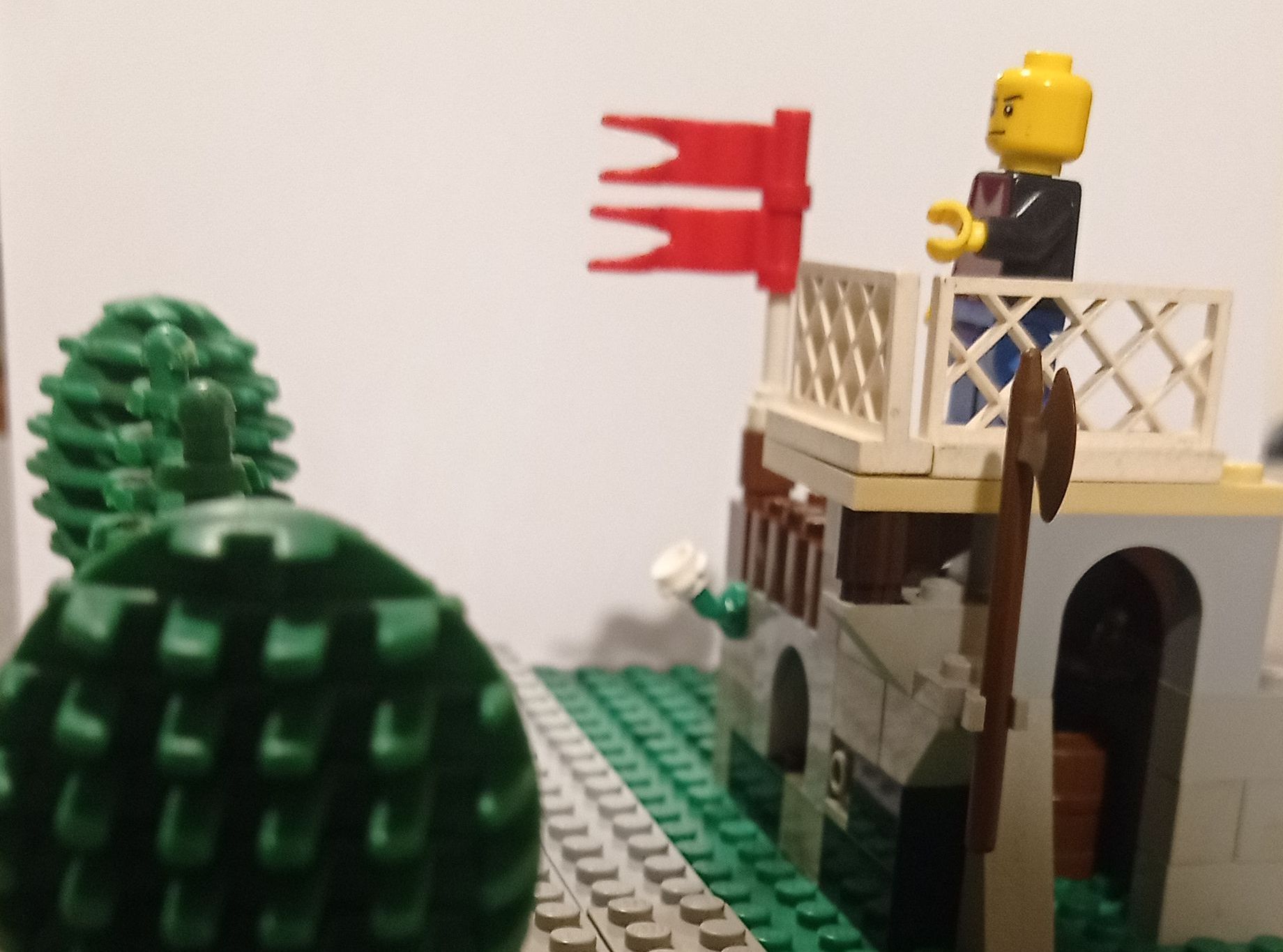 A lego man stands on a balcony with a red flag
