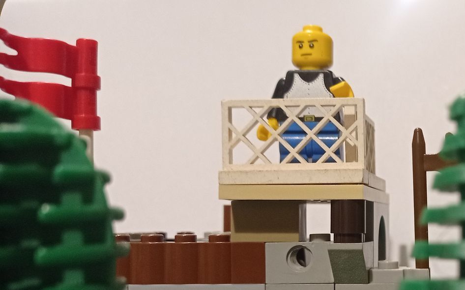 A lego man is standing on a balcony overlooking a building