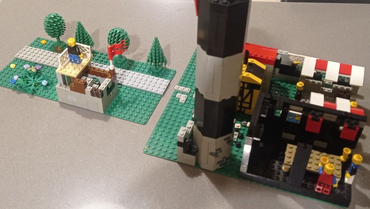 A lego model of a house and a lighthouse on a table