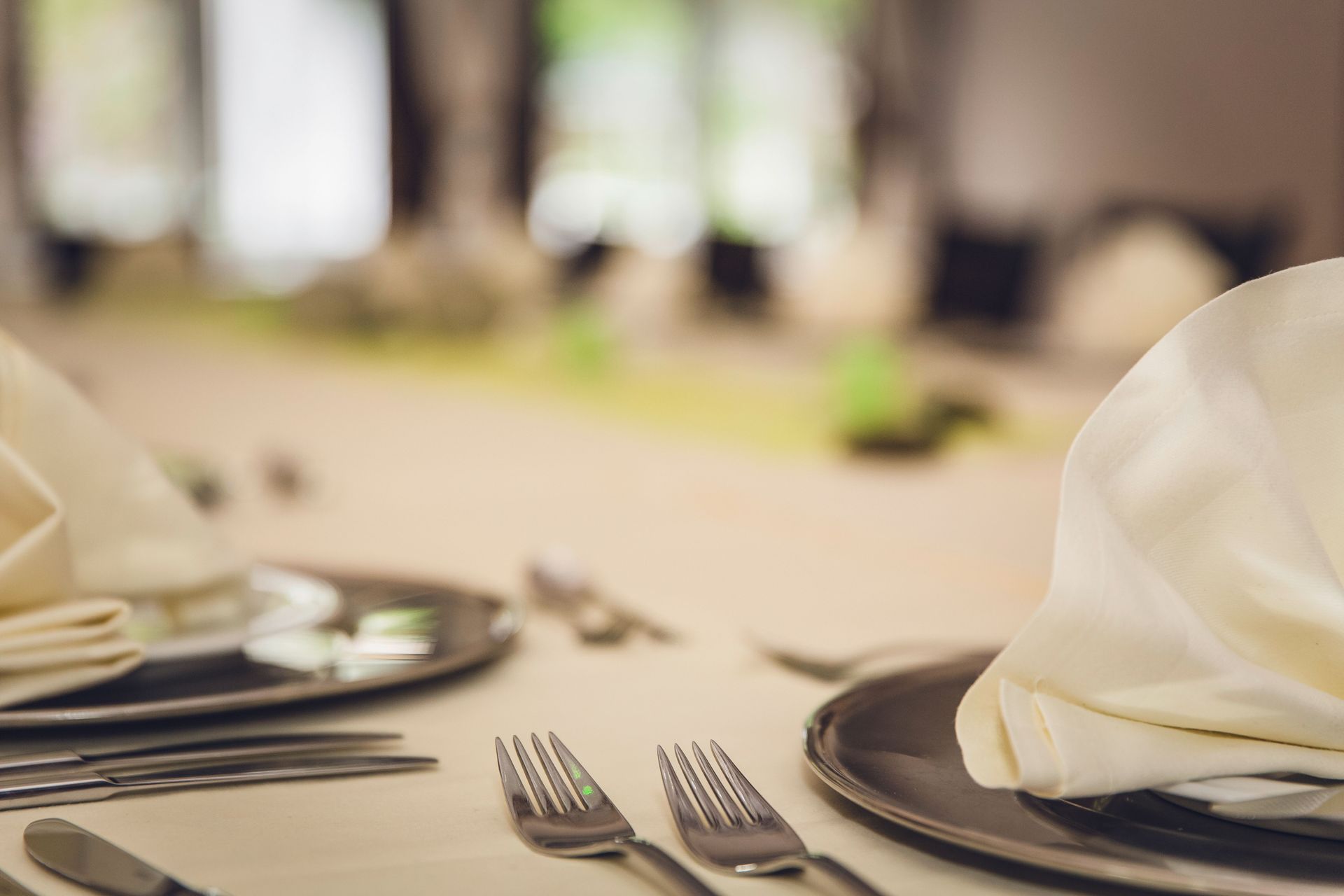 Set dining table with white napkins, silverware, and plates in a softly blurred restaurant setting