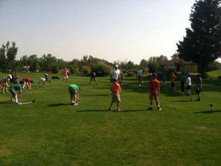 People in colorful shirts stretching on a grassy field outdoors.
