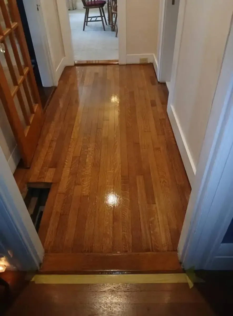 Hardwood hallway, polished wooden floor, doorway to a room, and another doorway to a room in the background.